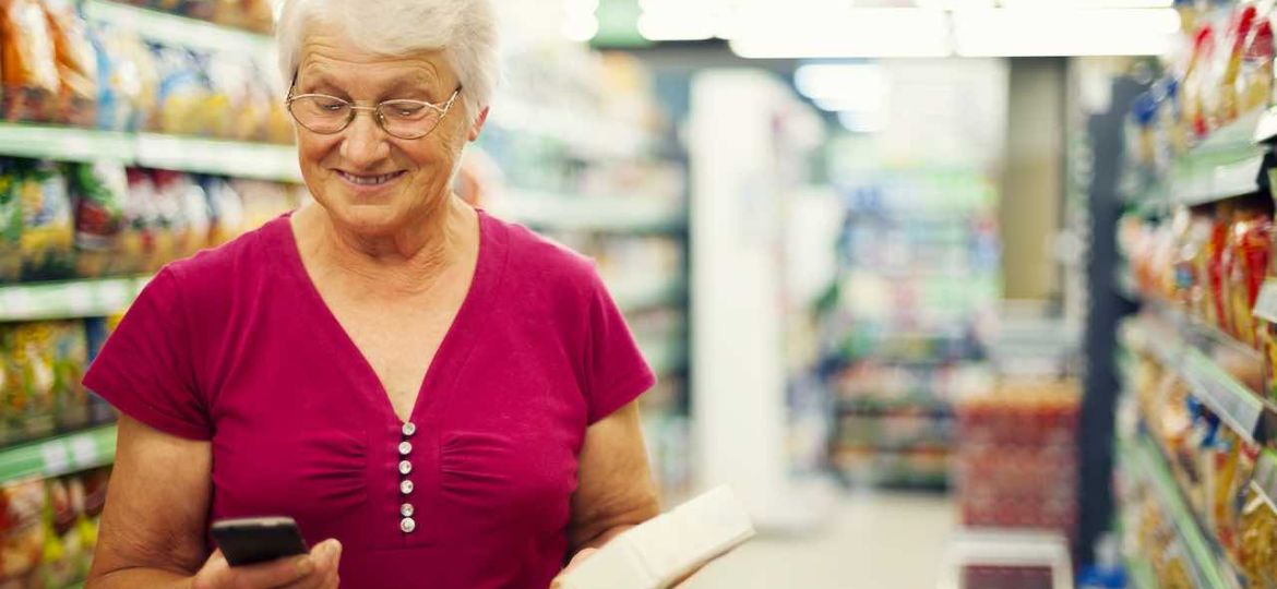 Senior woman texting on mobile phone at supermarket