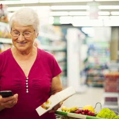 Senior woman texting on mobile phone at supermarket